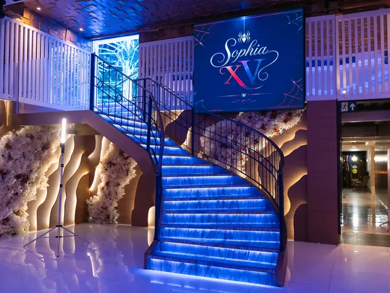 Escada iluminada em azul com o painel Sophia XV no alto